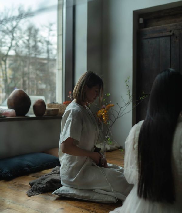 Person meditating peacefully near a large window with natural light.